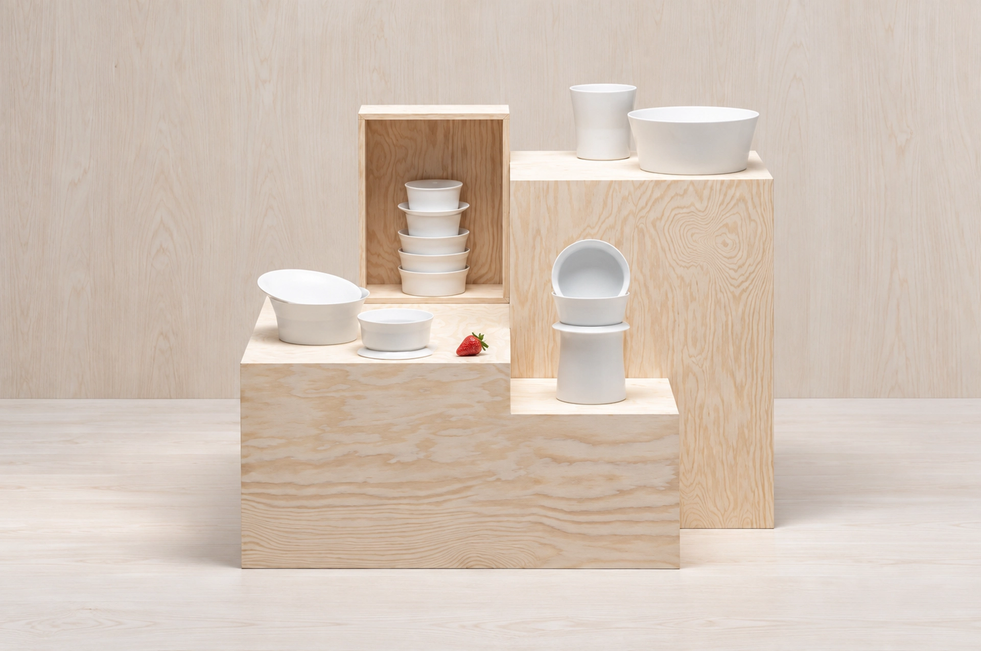 Wood-grain display blocks and tiered risers presenting white ceramic tableware